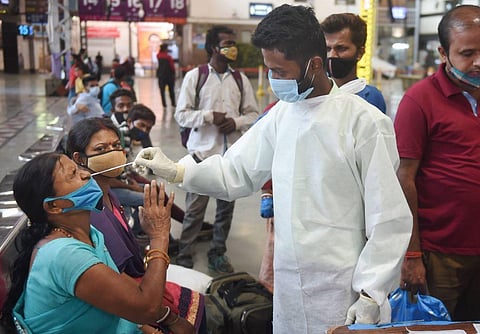 A health worker collects nasal sample from a passenger for COVID-19 test. (Photo | PTI)