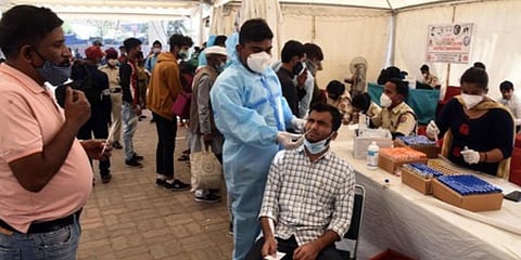 A health worker in PPE kit collects a swab sample from a traveller at Anand Vihar ISBT during coronavirus screening. (Photo | Parveen Negi, EPS)