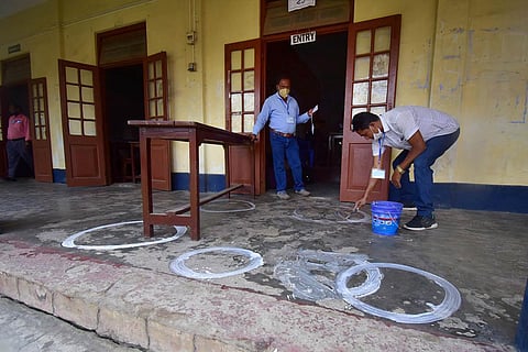 A polling officer draws markers on a floor to ensure social distancing as coronavirus cases spike across the country, on the eve of the second phase of Assam assembly polls, in Nagaon district. (Photo