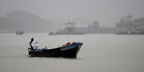 A Bangladeshi boatman uses a sheet in an attempt to shield himself from rain over the river Shitalakkhya near Dhaka. (File photo| AFP)