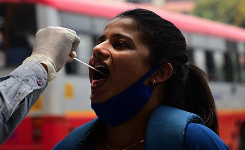A health worker collects a sample from a passenger for a RT-PCR test at the Majestic Bus Terminus, Bengaluru. (Photo | Ashishkrishna HP, EPS)