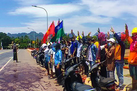 This handout photo from Eindu Youths shows protesters holding up three finger salute in front of red paint splashed on road in Hpa-an township in Myanmar's Karen state. (Photo | AFP