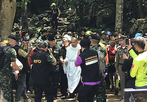 Rescuers help Phra Manas, center, walk out from the Tham Phra Sai Ngam cave in northern Thailand's Phitsanulok province on Wednesday. (Photo | AP)