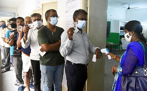 A polling officer checking temperature of voters at a polling booth in Saligramam. (Photo | Martin Louis, EPS)