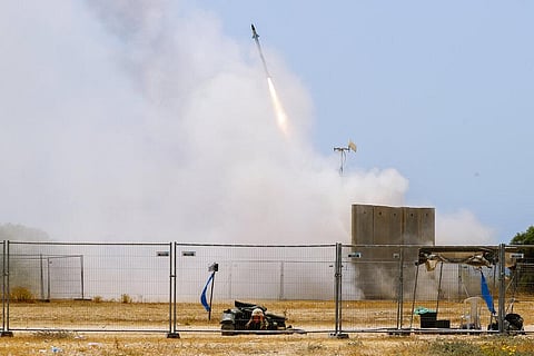 An Israeli soldier takes cover as an Iron Dome air defense system launches to intercept a rocket from the Gaza Strip, in Ashkelon, southern Israel, Tuesday, May 11, 2021. (Photo | AP)