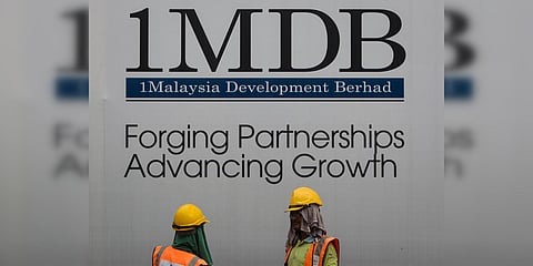 Construction workers chat in front of a billboard for state investment fund 1 Malaysia Development Berhad at the fund's flagship Tun Razak Exchange development in Kuala Lumpur. (File photo| AP)