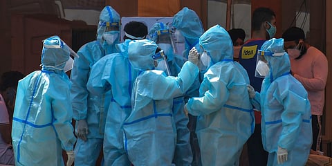Health workers and volunteers in personal protective suits wait to receive patients outside a COVID-19 hospital that was set up at a Sikh Gurdwara in New Delhi. (File photo| AP)