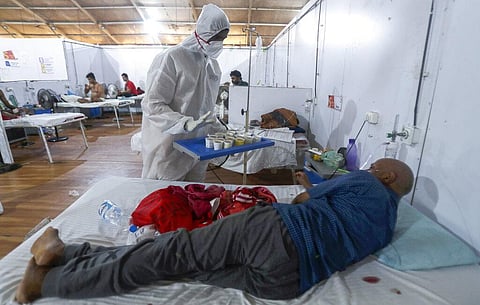 A health worker offers tea to a patient at the BKC jumbo field hospital, one of the largest COVID-19 facilities in Mumbai. (Photo | AP)