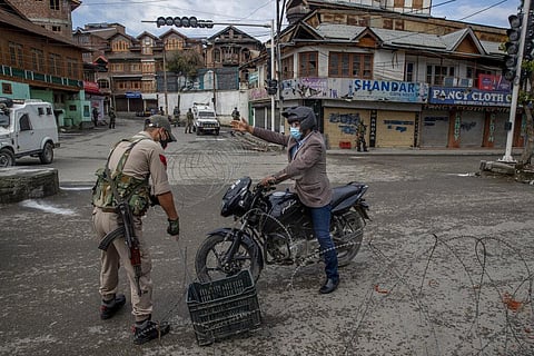 A Kashmiri motorcyclist requests to an Indian policeman to let him pass a temporary check point during lockdown to curb the spread of coronavirus. (Photo | AP)