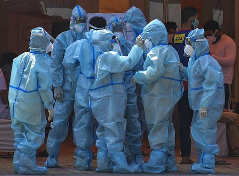 Health workers and volunteers in personal protective suits wait to receive patients outside a COVID-19 hospital that was set up at a Sikh Gurdwara in New Delhi. (Photo | AP)
