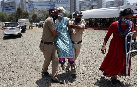 Police personnel help an elderly woman outside a vaccination center in Mumbai. (Photo | AP)