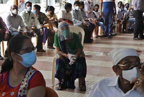 People wait to receive vaccine for COVID-19 outside a vaccination centre in Mumbai. (Photo | AP)