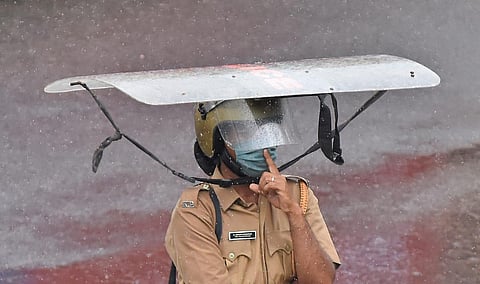 A cop braving rains uses a shield to save self from heavy showers in Thiruvananthapuram. (File | B P Deepu, EPS)