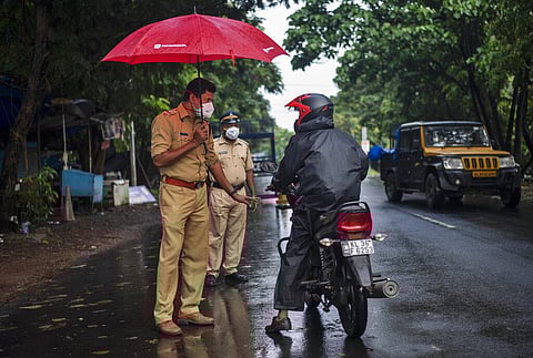 A police officer holds an umbrella to protect himself from the rain as he enforces a lockdown to curb the spread of the coronavirus in Kochi. (Photo | AP)