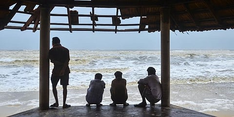 Local fishermans watch the effects of cyclone Touktae, at Panamburu beach area near Mangaluru, Sunday. (Photo | PTI)