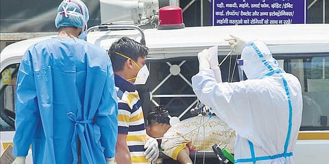 Medics wearing PPE check a COVID-19 patient upon her arrival at LNJP hospital in New Delhi on Sunday. (Photo | PTI)