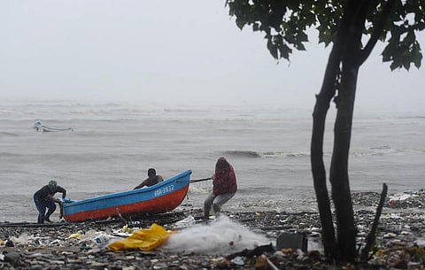 Fishermen pull their boat ashore to a safe place during the formation of cyclone Tauktae, at Bandra in Mumbai.  (Photo | PTI)