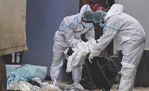 Workers wearing PPE suit pack Covid-19 waste to load on a vehicle for disposed at a state government run Covid hospital in Kolkata. (File Photo | PTI)