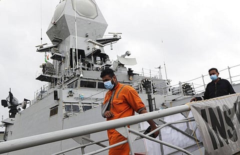 People rescued by the Indian navy from a barge that sank in the Arabian sea walk out from Indian naval ship INS Kochi in Mumbai. (Photo | AP)