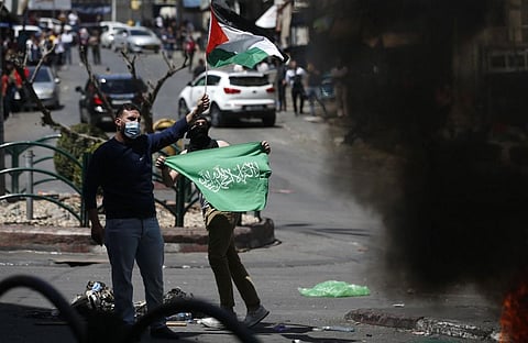 Palestinians demonstrators wave their national flag (Top) and green Hamas banner (bottom)  during protests against Israel's occupation, in the occupied West Bank  town of Hebron May 18.  (Photo | AFP)