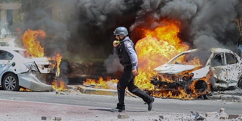 An Israeli firefighter walks next to cars hit by a missile fired from Gaza Strip, in the southern Israeli town of Ashkelon, Tuesday, May 11, 2021 (Photo | AP)