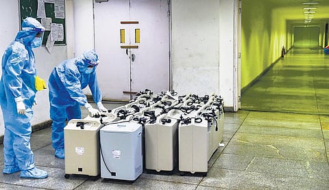 Health workers wearing PPE kits arrange oxygen concentrators at Yamuna Sports Complex Covid care centre in New Delhi. (Photo | PTI)