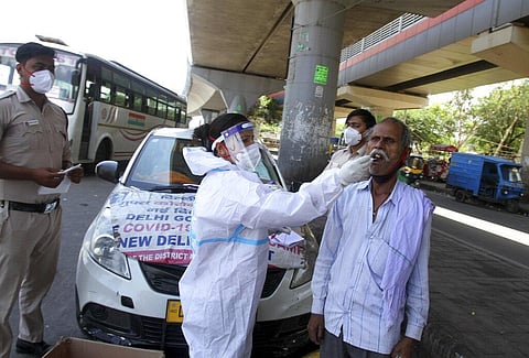 A heath worker in protective suit takes mouth swab sample of a man to test for COVID-19 in New Delhi. (Photo | AP)