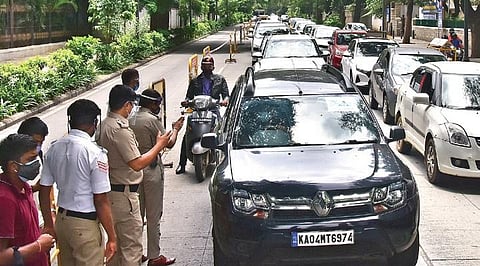 Police personnel stop vehicles and check them for violations during the statewide lockdown, on Nrupathunga Road in Bengaluru on Friday | vinod kumar t