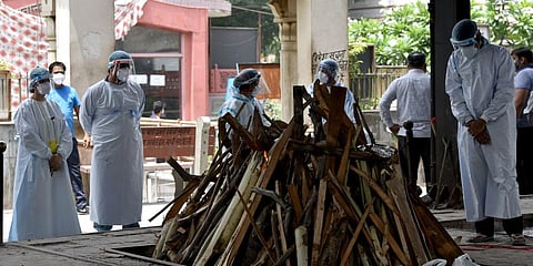 A relative performs the final rites of the COVID-19 victim, at a crematorium in New Delhi. (Photo | ANI)
