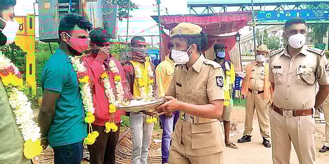Police personnel garland motorists for violating lockdown restrictions in Madanayakanahalli.