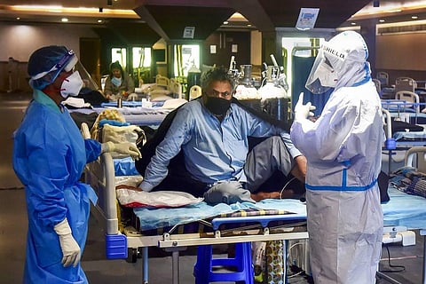 Health workers attend to a COVID-19 patient at Shehnai Banquet Hall COVID-19 isolation centre, in New Delhi. (Photo | PTI)