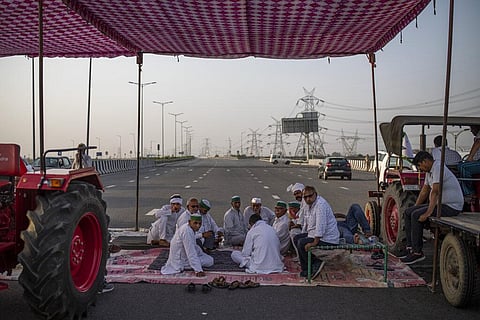 Farmers sit in a tent during a 24-hour blockade of a major expressway as part of their ongoing protests against new farm laws in Dasna. (File Photo | AP)