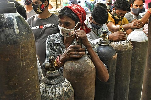 People wait to refill oxygen cylinders for COVID-19 patients at a gas supplier facility in New Delhi. (Photo | AP)