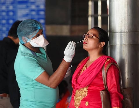 A health worker collects swab sample of a passenger at a COVID-19 testing counter at New Delhi railway station. (Photo | PTI)