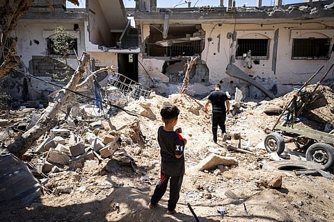 A Palestinian kid standing in a clearing strewn with debris from an Israeli airstrike in Gaza.