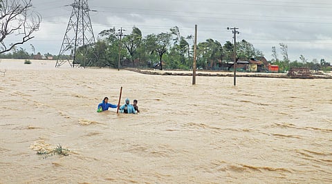 A family  wades through waist-deep water to reach a safer place near Dhamra port in Bhadrak that was battered by cyclone Yaas