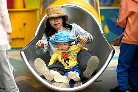 A mother and her baby playing on a slide at Wukesong shopping district in Beijing. (Photo | AFP)