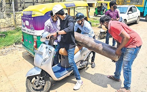 As Bengaluru’s demand for oxygen peaks, a group of people are seen trying to transport an oxygen cylinder on a two-wheeler, in Bengaluru on Tuesday | Shriram BN