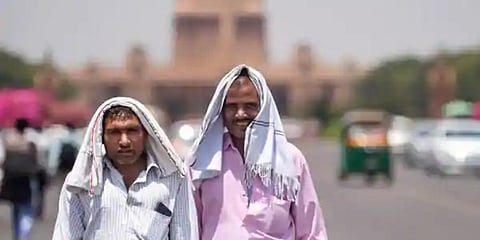 Pedestrians cover their heads to shield from the scorching sun, on a hot summer day, in New Delhi. (Photo | PTI)