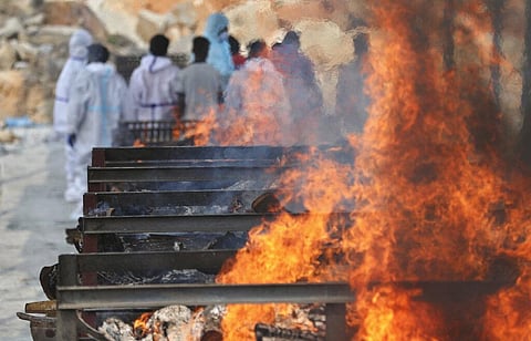 Family members perform last rites of a person who died of COVID-19 as funeral pyres of other victims burn at an open crematorium. (Photo | AP)