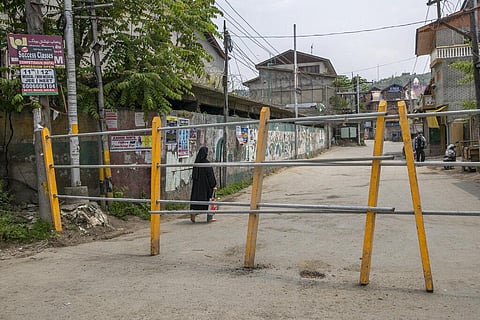 A Kashmiri woman walks past a temporary barricade set up by authorities inside an area declared red zone by authorities to curb the spread of coronavirus in Srinagar. (Photo | AP)