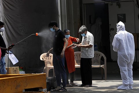 A health worker sprays disinfectant on a person who was discharged after being treated for COVID-19 at a field hospital in Mumbai. (Photo | AP)
