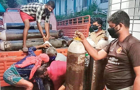 Workers load oxygen cylinders meant to be transported to the Aluva Government Hospital on Saturday | Express