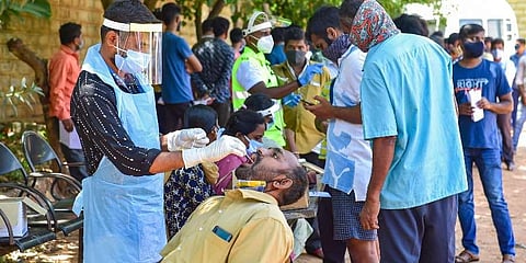 A medic collects a swab sample from a man for the Covid-19 testing, in Bengaluru. (Photo | PTI)