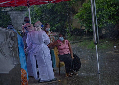 Sri Lankan health officials collect swab samples from people to test for the coronavirus during a brief spell of rain in Colombo. (Photo | AP)