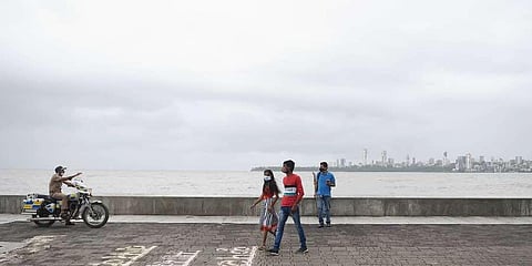 A police personnel patrols at Marine Drive as he requests visitors to move away from the shore area, during high tide in Mumbai. (Photo | PTI)