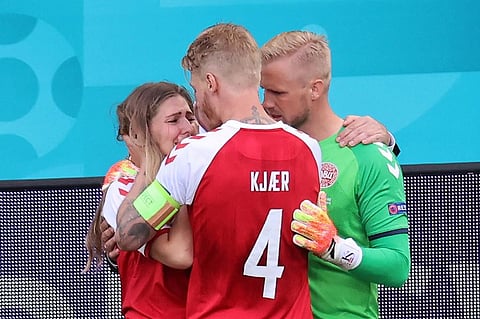 Kasper Schmeichel (R) and Simon Kjaer (C) comfort Sabrina Kvist Jensen, partner of teammate Christian Eriksen, after he collapsed on the pitch. (Photo | AFP)