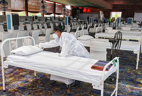 A worker prepares a bed at an oxygen centre for COVID-19 patients, operated by Hemkunt Foundation, in Gurugram. (File photo | PTI)