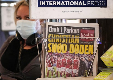 A front-page of a newspaper shows the shocked Danish soccer team escorting player Christian Eriksen, at a newsstand at the central station in Copenhagen, Denmark. (Photo | AP)