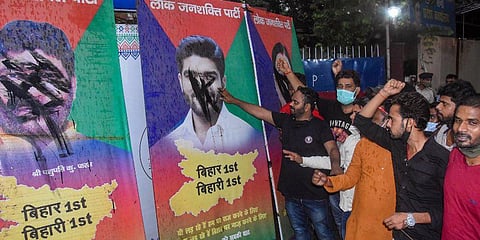 Chirag Paswan supporters paint the posters of rebel leaders of Lok Janshakti Party black, outside party office in Patna. (Photo | PTI)